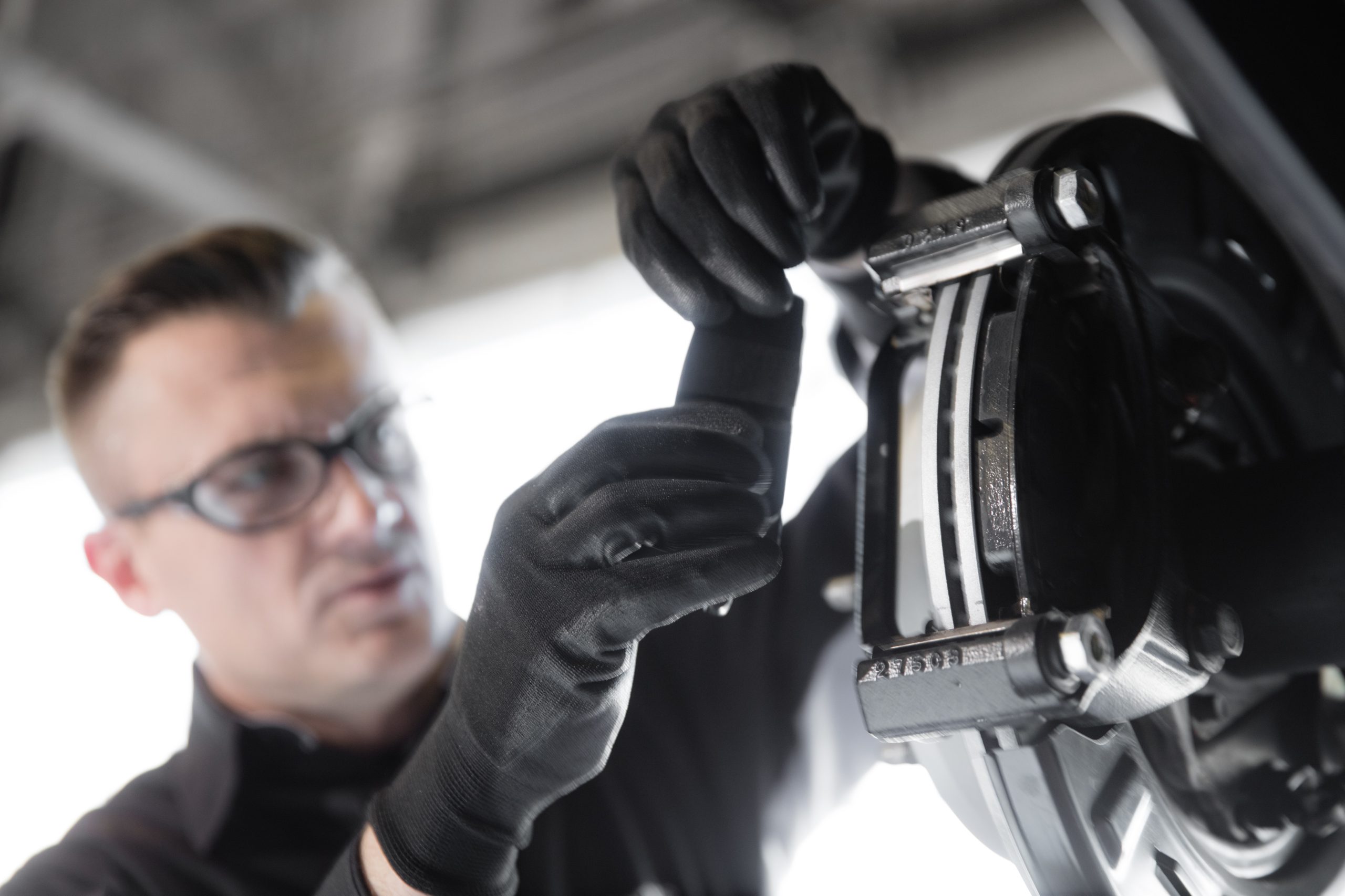 A mechanic in glasses installing brake pads on a vehicle