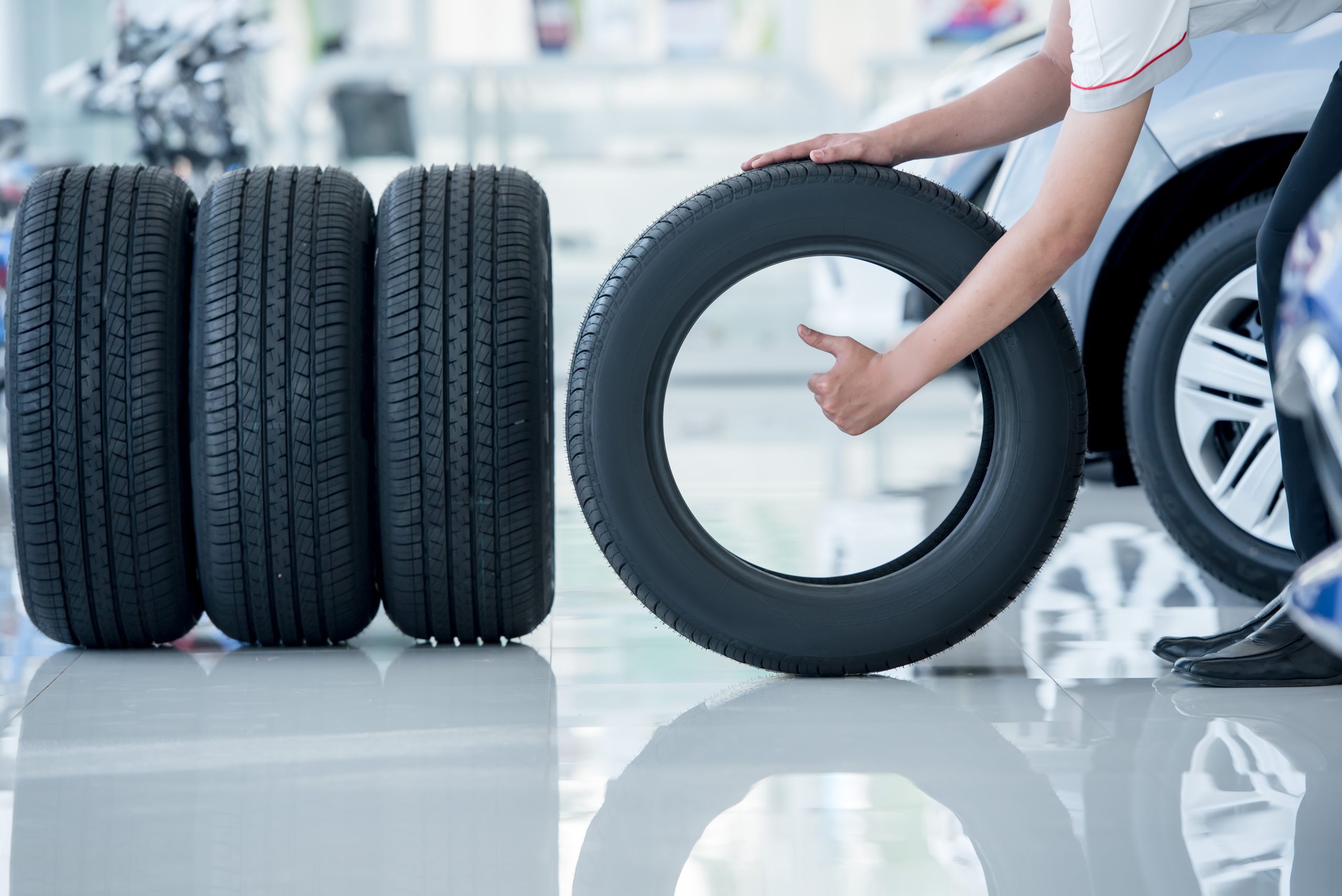person giving a thumbs-up through a car tire next to a row of three tires
