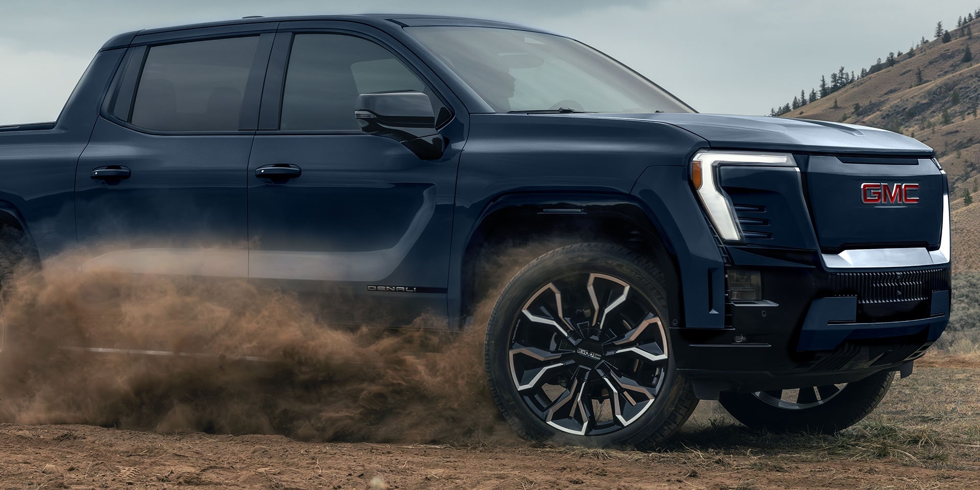 GMC Sierra EV pickup driving off-road with dust
